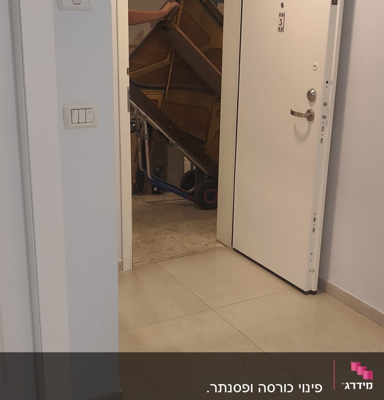 פסנתר מועבר דרך דלת פתוחה במסדרון